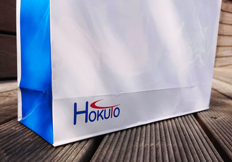 ロゴの色で使用されている青色で紙袋のマチ部分をベタ印刷