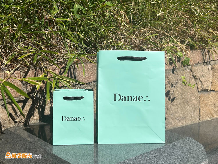 ターコイズブルーの上品なカラーと黒ロゴの組み合わせが印象的なオリジナル紙袋