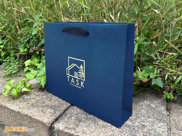 紙袋全体をコーポレートカラーである深みのあるネイビーに全面印刷