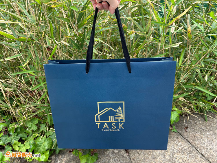 黒のハンドル紐が紙袋全体を引き締め、スタイリッシュで上品な印象