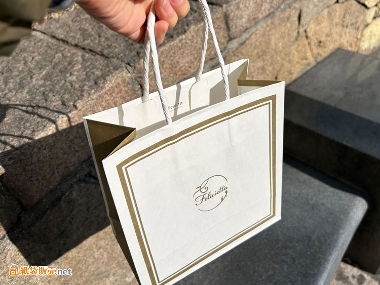 白色の紙単紙ハンドルが袋本体の上品なデザインと調和