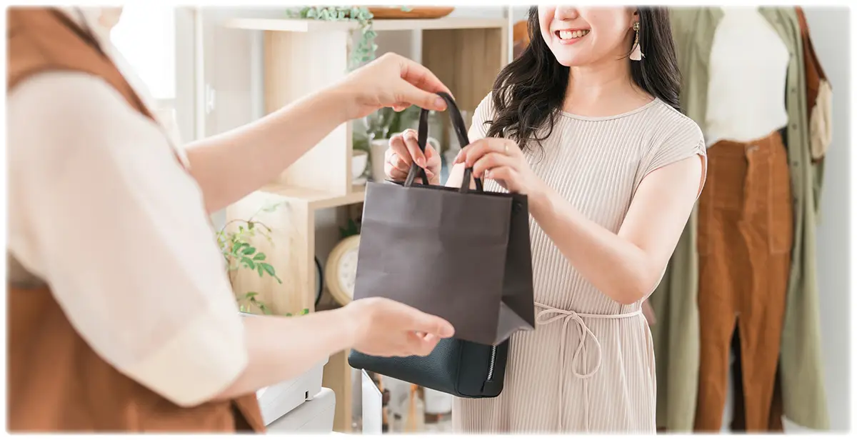 商品の入ったショッパーを受け取るお客様